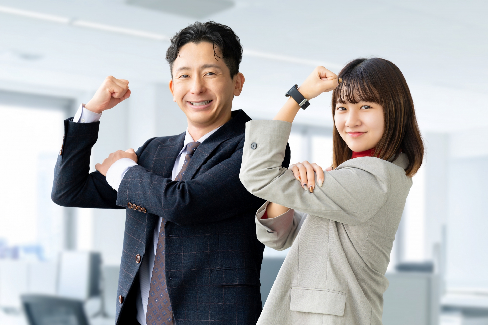 力こぶをアピールする会社員の男女